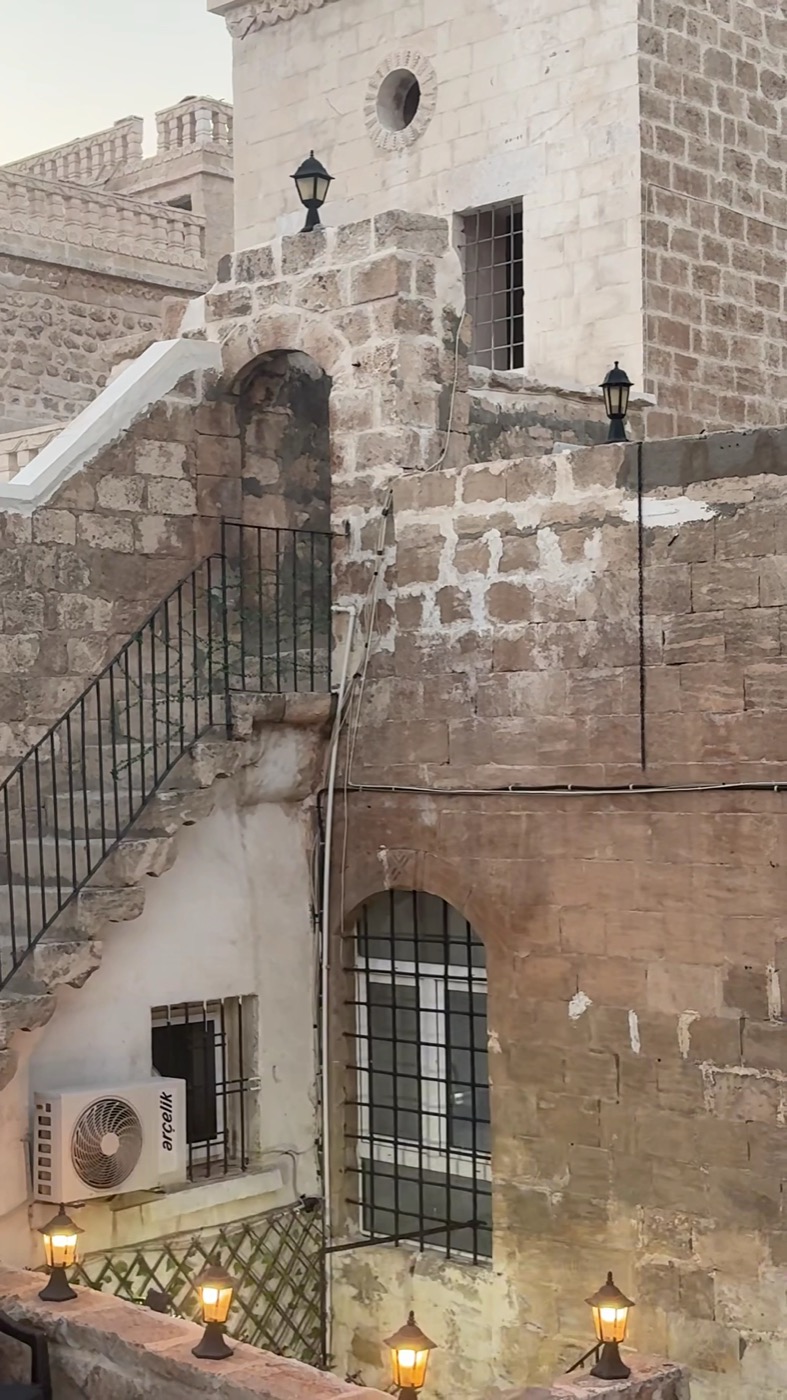 Konağın kemerli kapısı, taş merdiveni ve akşam yanan duvar lambaları